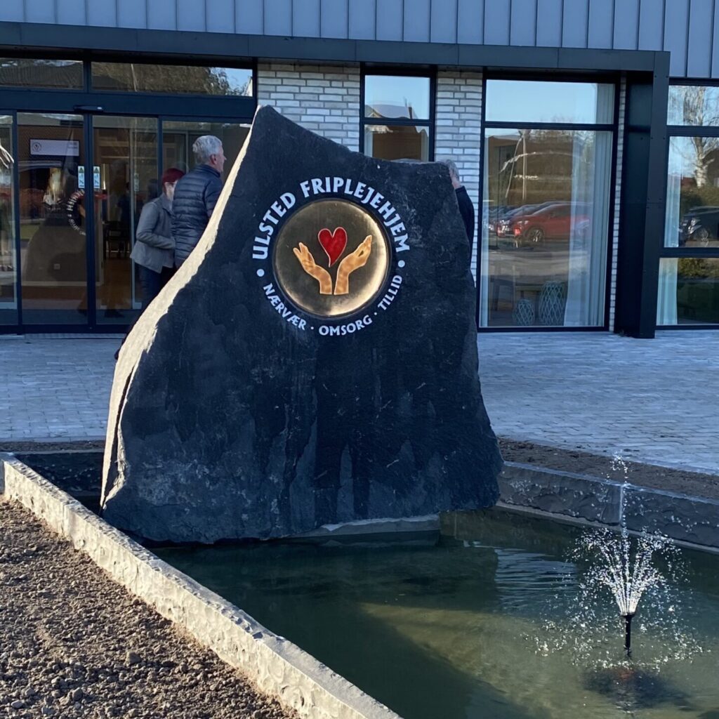 Stenskulptur i springvand foran plejehjem med håndlavet glaskunst fra Hejslet Design